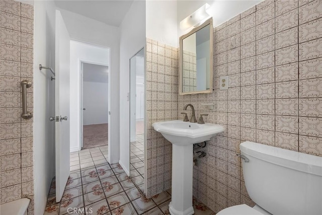 bathroom featuring tile patterned flooring, toilet, and tile walls