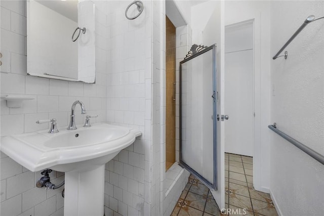 bathroom with sink, tile patterned flooring, backsplash, tiled shower, and tile walls