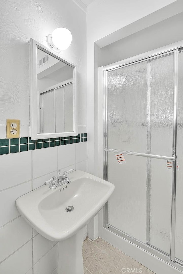 bathroom featuring a shower with shower door, tile walls, and tasteful backsplash