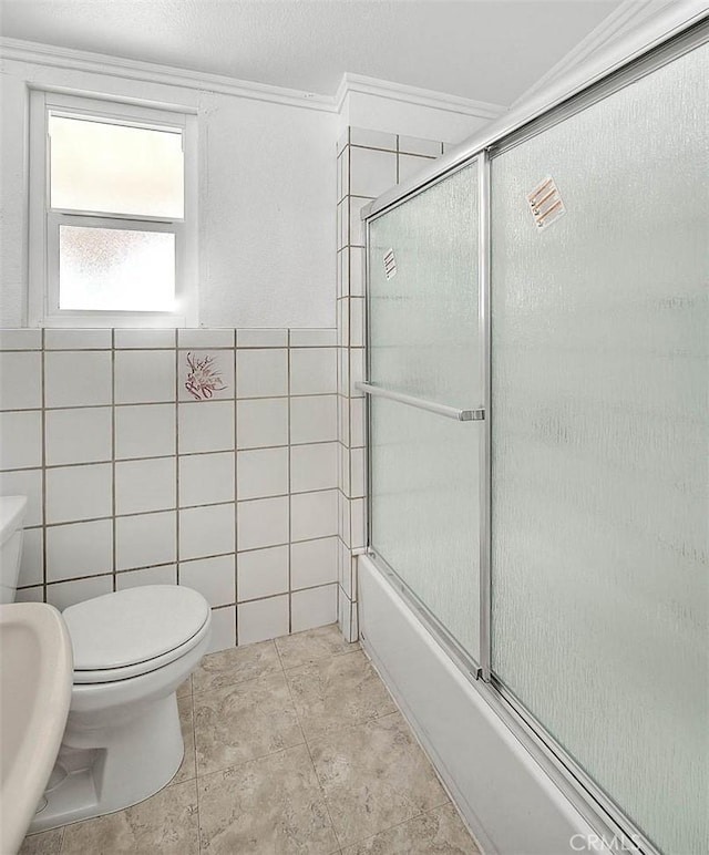 bathroom featuring shower / bath combination with glass door, tile patterned flooring, toilet, and tile walls