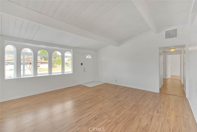 spare room featuring lofted ceiling with beams and light hardwood / wood-style floors