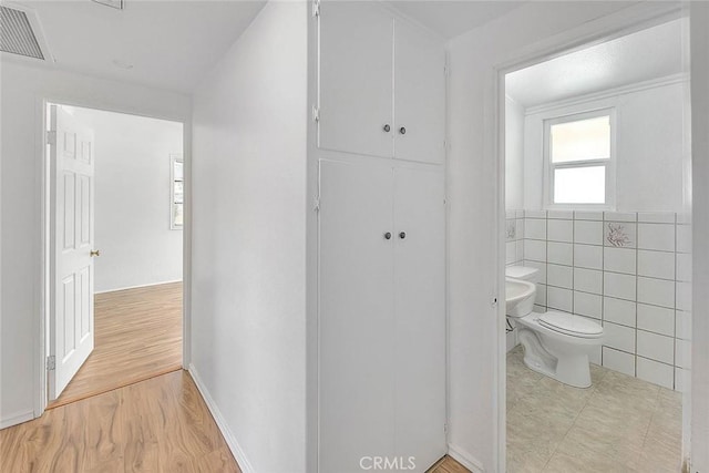 bathroom featuring hardwood / wood-style floors, tile walls, and toilet