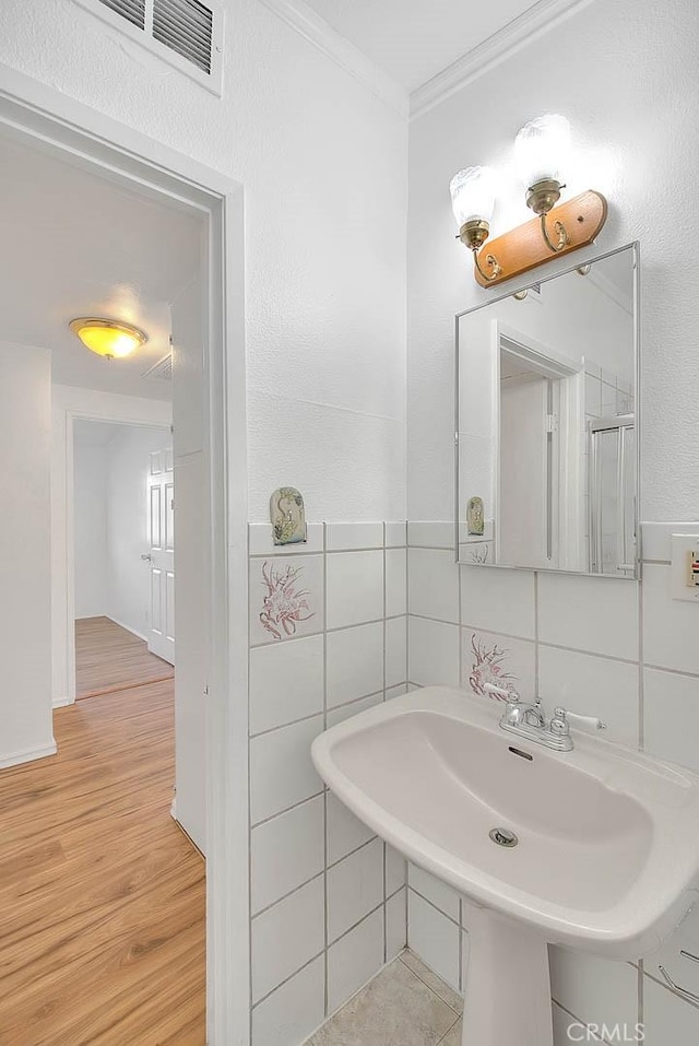 bathroom featuring hardwood / wood-style floors, ornamental molding, and sink