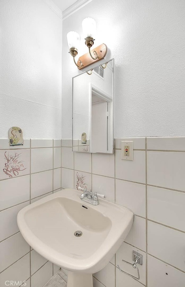 bathroom featuring crown molding, sink, and tile walls