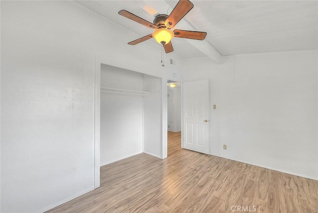 unfurnished bedroom featuring vaulted ceiling with beams, a closet, light hardwood / wood-style flooring, and ceiling fan