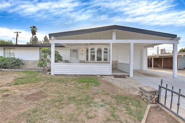 rear view of property with a carport, a porch, and a garage