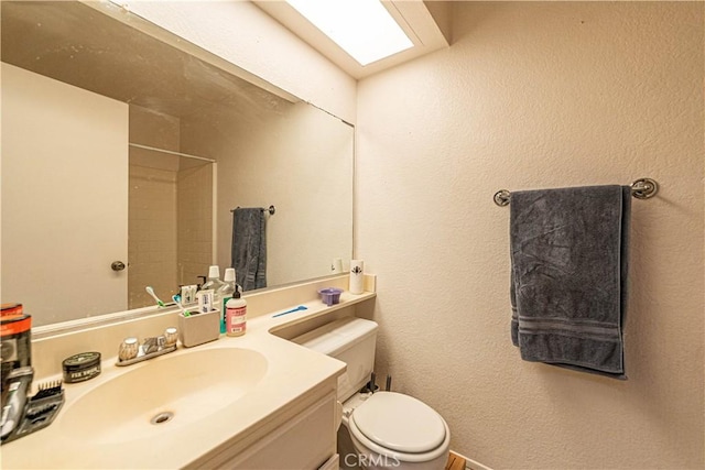 bathroom with walk in shower, vanity, and toilet