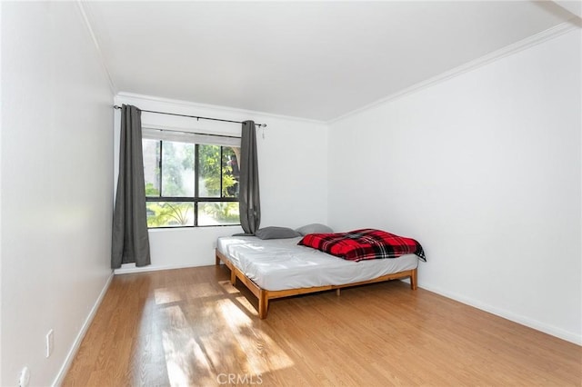 bedroom with ornamental molding and light hardwood / wood-style flooring