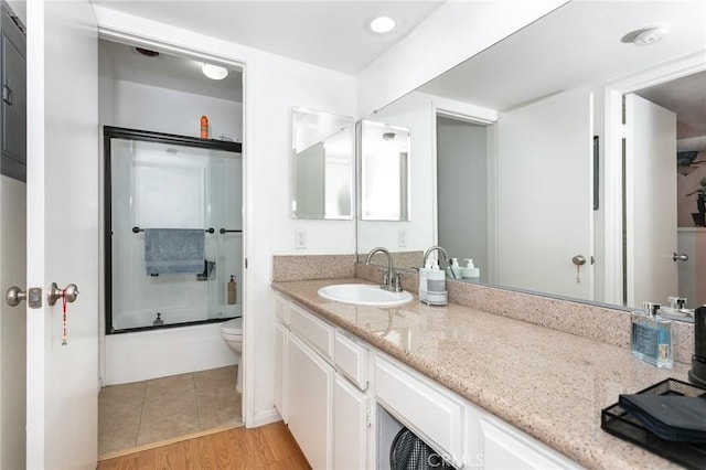 22100 Burbank Blvd Unit 106A, Woodland Hills, CA 91367 - bathroom featuring toilet, vanity, wood finished floors, and combined bath / shower with glass door