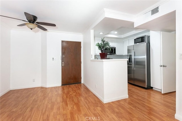 kitchen with white cabinets, light wood-type flooring, stainless steel appliances, and ornamental molding