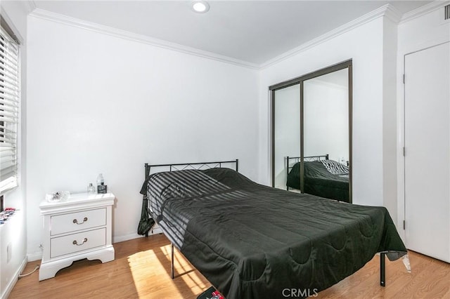 bedroom featuring light hardwood / wood-style floors, a closet, and crown molding