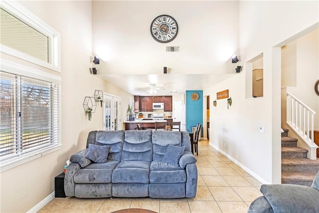 tiled living room featuring ceiling fan and french doors