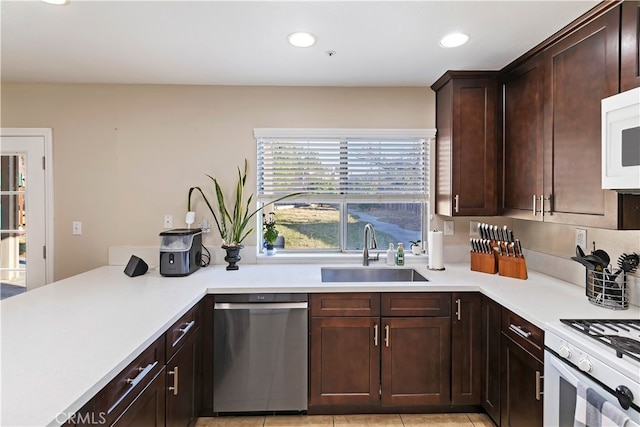 kitchen with dark brown cabinetry, dishwasher, sink, light tile patterned flooring, and stove