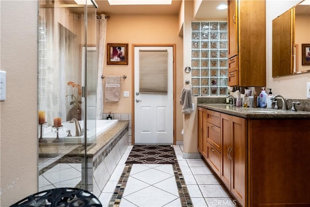 bathroom with vanity, tiled bath, tile patterned floors, and a skylight