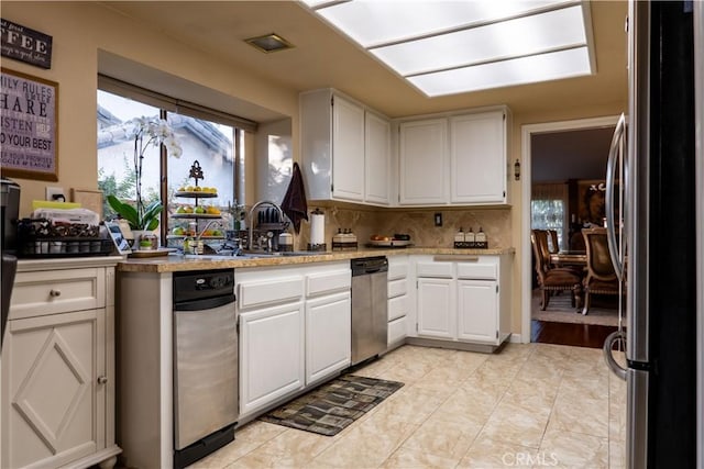 kitchen featuring sink, light tile patterned floors, stainless steel fridge, decorative backsplash, and white cabinets