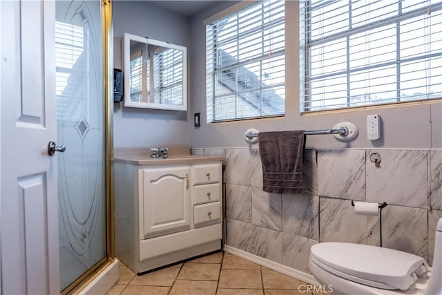 bathroom with vanity, tile patterned floors, toilet, tile walls, and a shower with shower door