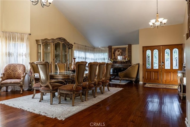 dining space with dark hardwood / wood-style flooring, high vaulted ceiling, french doors, and an inviting chandelier