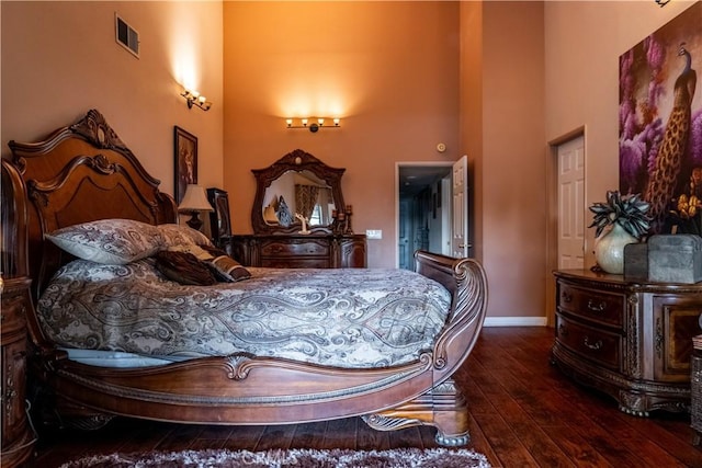 bedroom with a towering ceiling and dark wood-type flooring