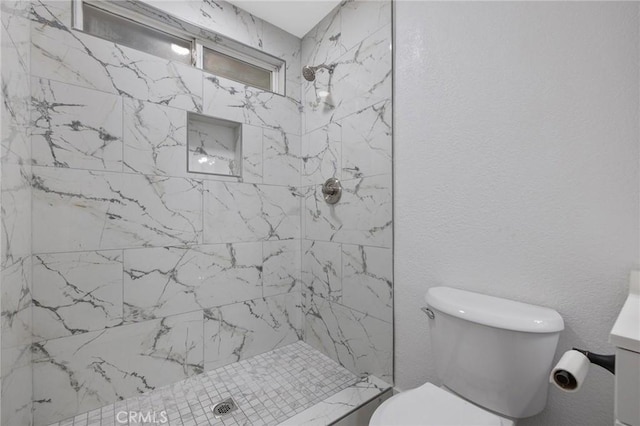 bathroom with vanity, toilet, and a tile shower