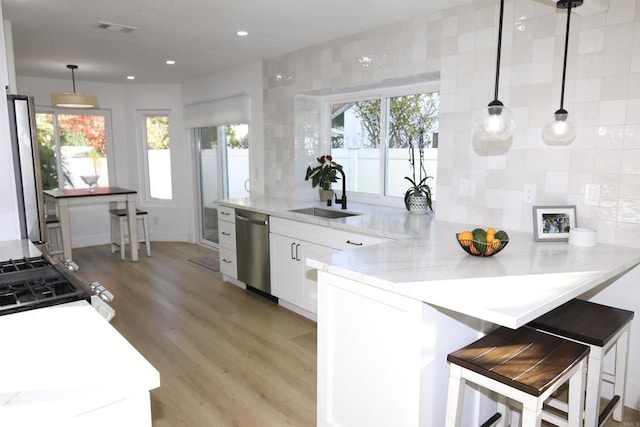 kitchen featuring sink, white cabinetry, a kitchen breakfast bar, stainless steel appliances, and kitchen peninsula