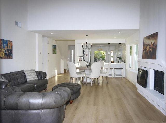 living room featuring an inviting chandelier, a towering ceiling, and light hardwood / wood-style floors