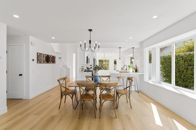 dining area featuring baseboards, light wood-type flooring, an inviting chandelier, and recessed lighting