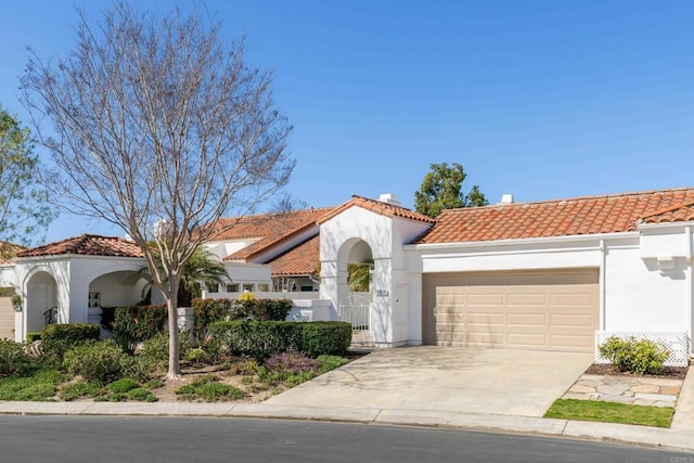 mediterranean / spanish house featuring a garage, stucco siding, concrete driveway, and a tiled roof