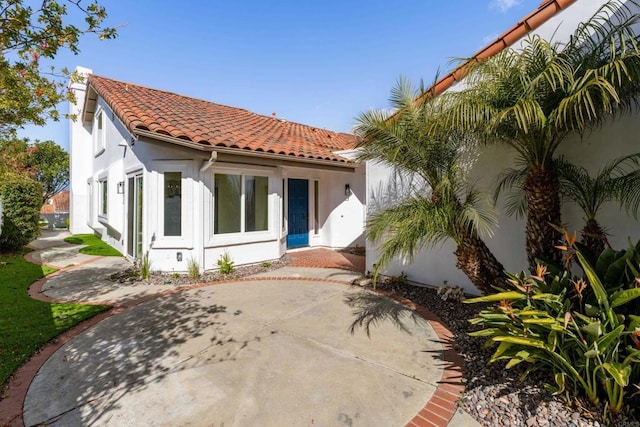 back of house featuring a tile roof and stucco siding