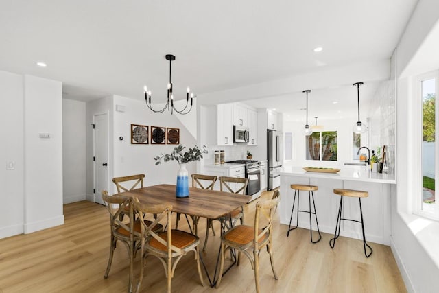 dining space featuring a chandelier, light wood-type flooring, and recessed lighting