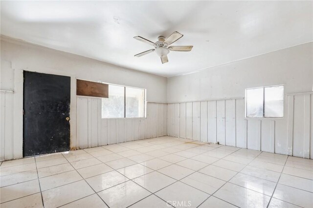 tiled spare room with ceiling fan