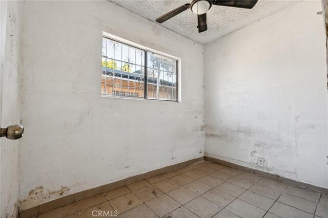 unfurnished room with ceiling fan and a textured ceiling