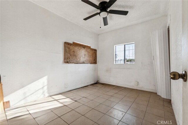 empty room with ceiling fan and light tile patterned floors