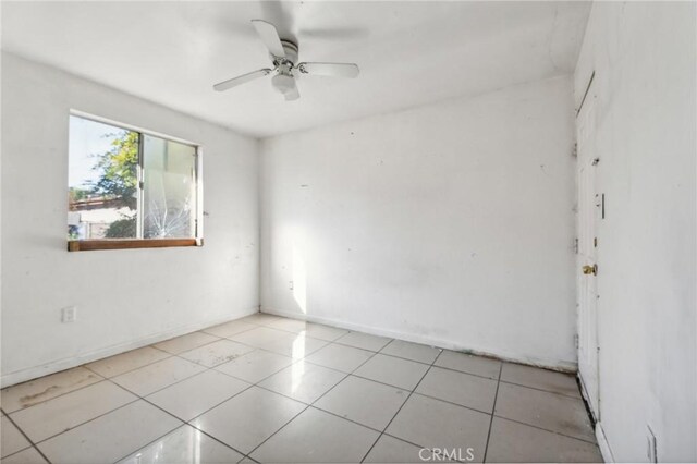 empty room with ceiling fan and light tile patterned floors