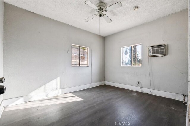 unfurnished room featuring dark hardwood / wood-style flooring, a wall unit AC, a wealth of natural light, and ceiling fan