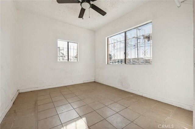 tiled spare room with plenty of natural light, ceiling fan, and a textured ceiling