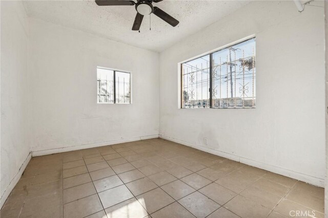 2853 E 6th St, Los Angeles, CA 90023 - tiled spare room with plenty of natural light, a textured ceiling, ceiling fan, and baseboards
