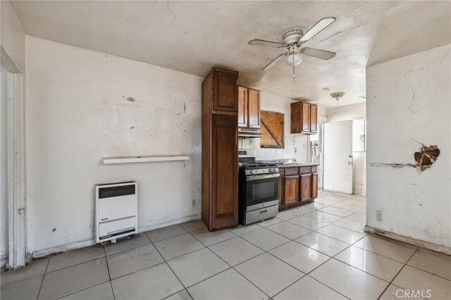 kitchen with ceiling fan, stainless steel gas range oven, light tile patterned floors, and heating unit