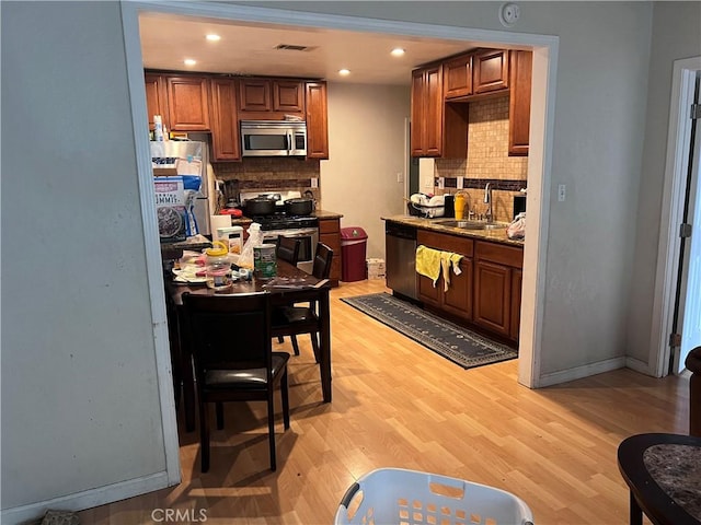 kitchen with backsplash, stainless steel appliances, light hardwood / wood-style flooring, and sink