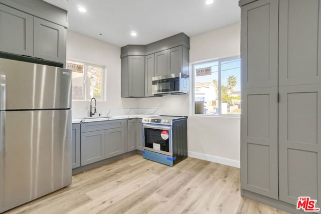 kitchen featuring gray cabinets, sink, stainless steel appliances, and light hardwood / wood-style flooring