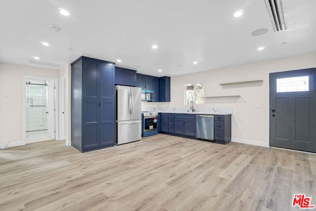 kitchen featuring plenty of natural light, blue cabinets, stainless steel appliances, and light hardwood / wood-style floors