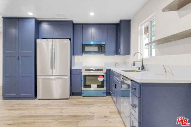 kitchen with blue cabinets, sink, light wood-type flooring, light stone countertops, and appliances with stainless steel finishes