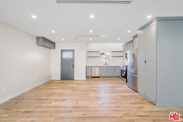 kitchen featuring gray cabinets, sink, stainless steel appliances, and light wood-type flooring