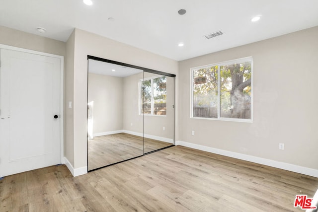 unfurnished bedroom featuring a closet and light hardwood / wood-style floors