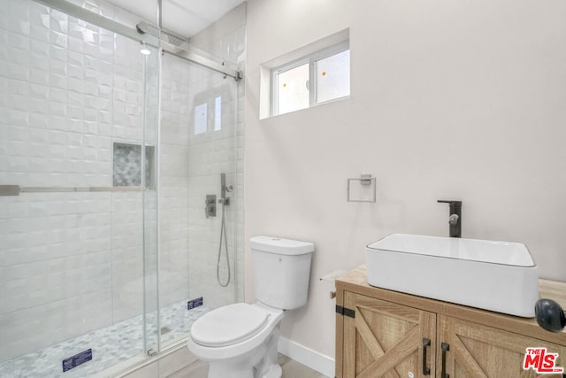 bathroom with vanity, toilet, and a shower with door