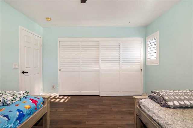 bedroom with dark hardwood / wood-style floors, ceiling fan, and a closet