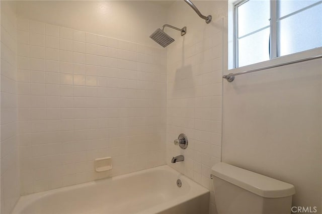 bathroom featuring tiled shower / bath combo and toilet