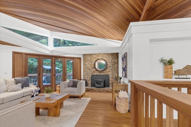 living room with a wood stove, wooden ceiling, light hardwood / wood-style floors, and vaulted ceiling