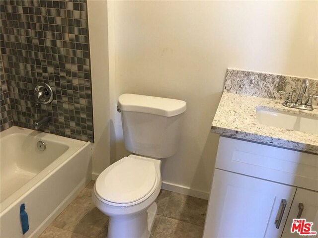 full bathroom featuring vanity, tiled shower / bath combo, and toilet