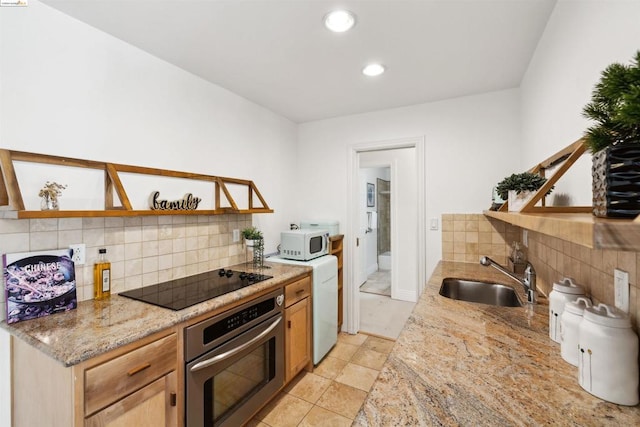 kitchen featuring backsplash, black electric stovetop, oven, sink, and light stone counters