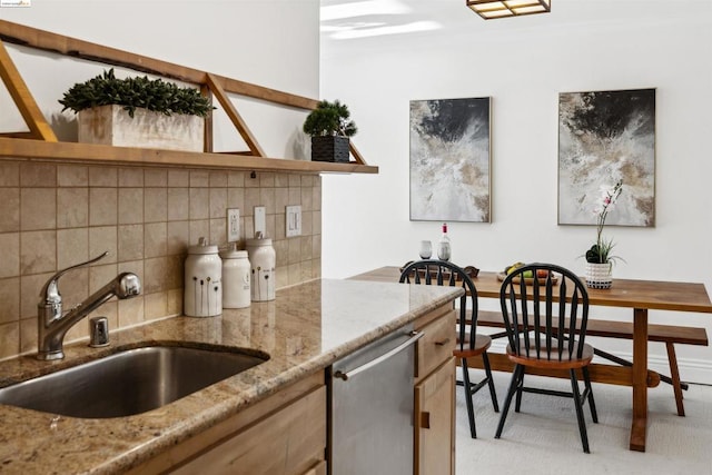 kitchen with backsplash, dishwasher, sink, and light stone countertops